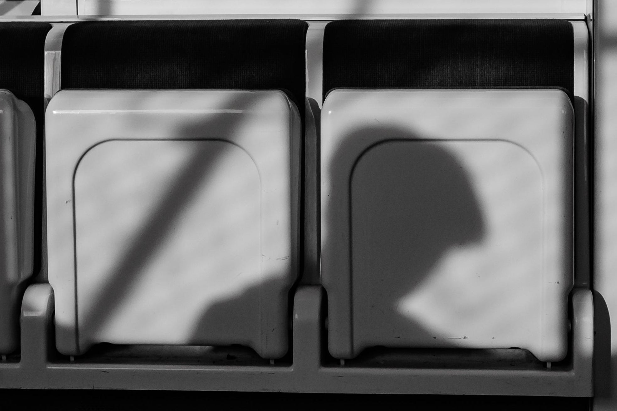 Black and white photo of a train seat with a person's silhouette.